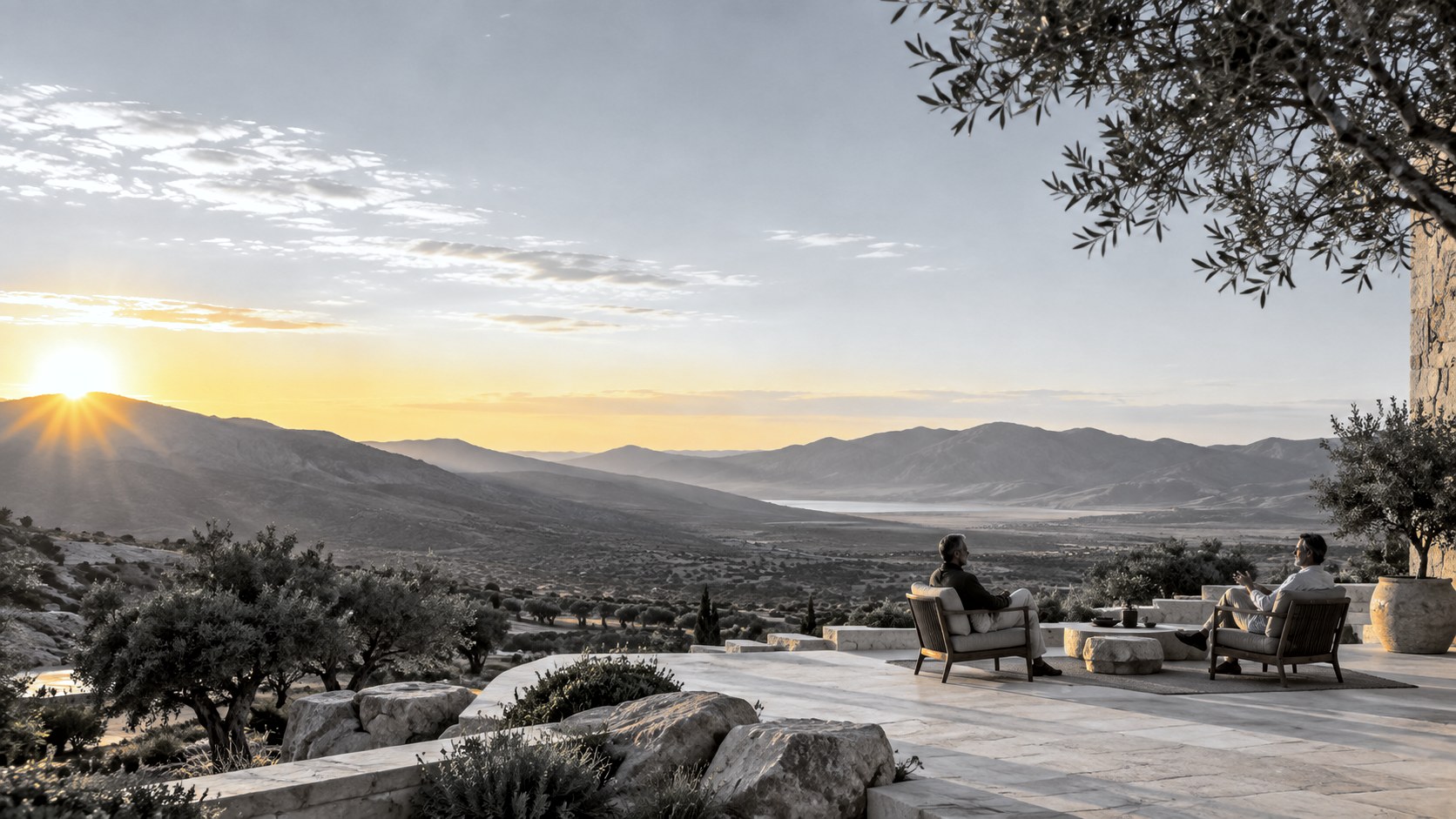 Two executives in conversation on a terrace above an olive valley at sunset